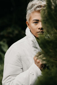 Portrait of young man standing by plant
