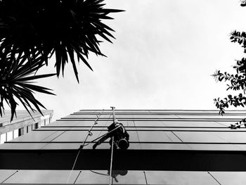 Low angle view of man working on rope against sky