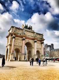 People at town square against cloudy sky