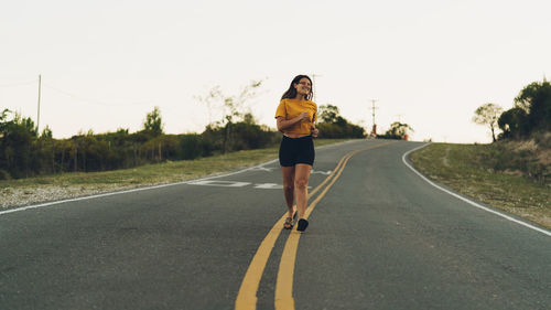 Full length of woman running on road against sky