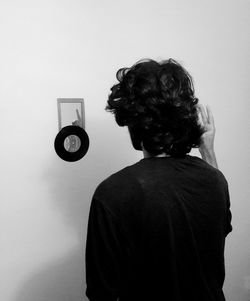 Rear view of man standing in front of mirror with record