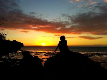 Silhouette man on beach against sky during sunset