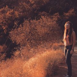 Full length portrait of woman standing on field during autumn