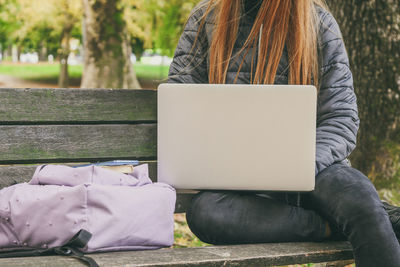 Midsection of woman using laptop while sitting on sofa