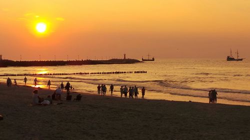 Silhouette people on beach at sunset