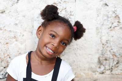 Portrait of cute smiling girl against wall