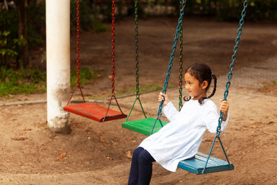 Thoughtful girl on swing at playground
