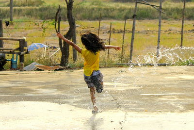 Water spraying on girl running on footpath