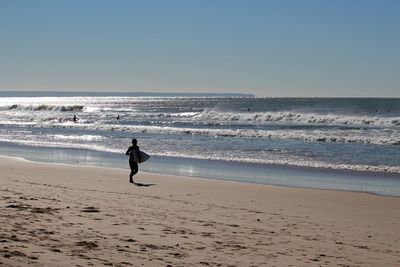 Silhouette surfer running at beach