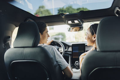 Rear view of mother sitting near son driving car