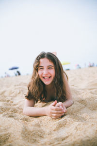 Little girl lying on the sand having fun and laughing