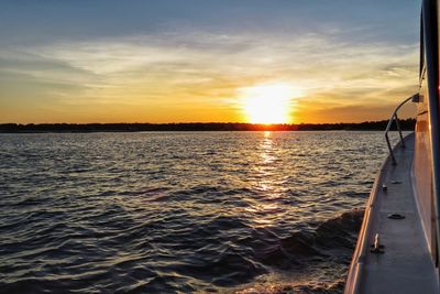 Boat sailing in sea against sky during sunset