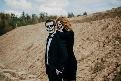 A couple in love is sitting hugging against the backdrop of mountains celebrating halloween in costu