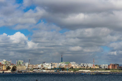 Sea by buildings against sky in city