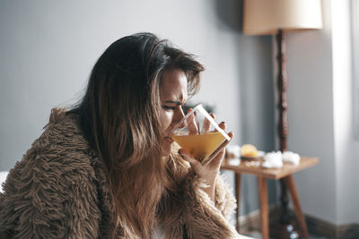 Young woman drinking water at home