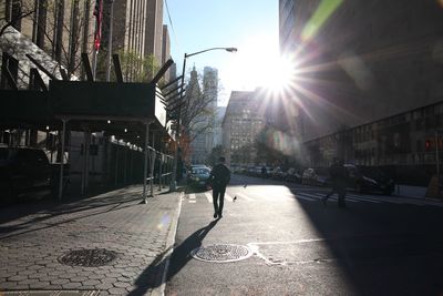 People on sidewalk in city against sky