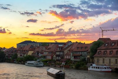 Boats moored in city against sky during sunset