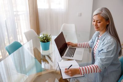 Portrait of young woman using laptop at home