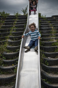 Portrait of boy playing on slide at park