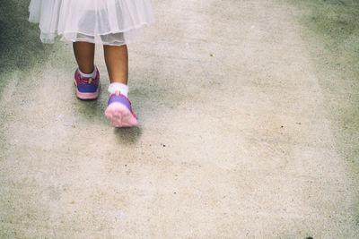 Low section of girl walking on footpath