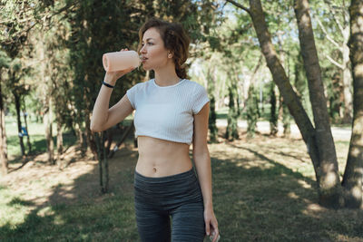 Full length of beautiful young woman standing against trees