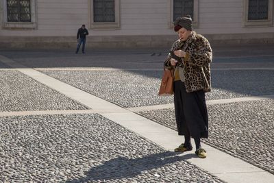 Woman with umbrella standing on street