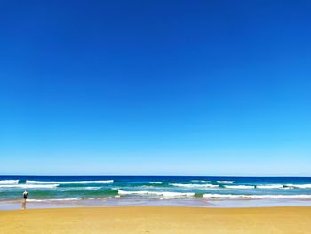 Scenic view of beach against clear blue sky