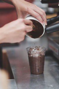 Cropped image of hand pouring coffee in glass