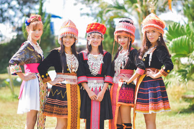 Full length portrait of smiling young women standing outdoors