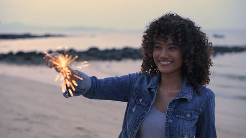 Portrait of smiling young woman standing on beach