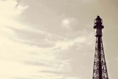 Low angle view of communications tower and building against sky