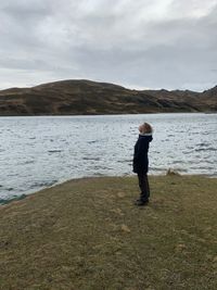 Woman looking up while standing by river during winter