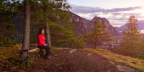 Woman sitting on mountain against sky