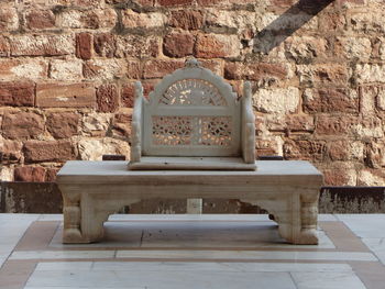 Empty bench against brick wall