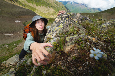 Brave young climber fearlessly climbs a steep stone wall in the mountains, overcoming obstacles. a