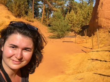 Portrait of smiling young woman against trees