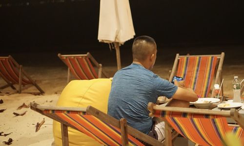 Rear view of man sitting on chair