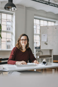 Portrait of smiling businesswoman sitting at desk in office
