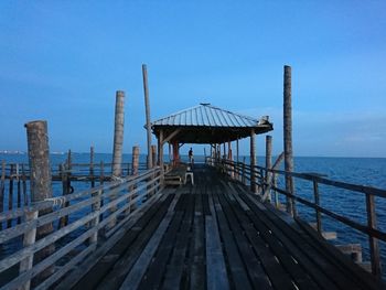 Pier over sea against clear blue sky