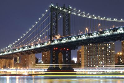 Illuminated bridge over river at night