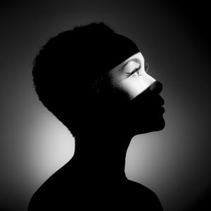 Close-up of young woman in light against black background