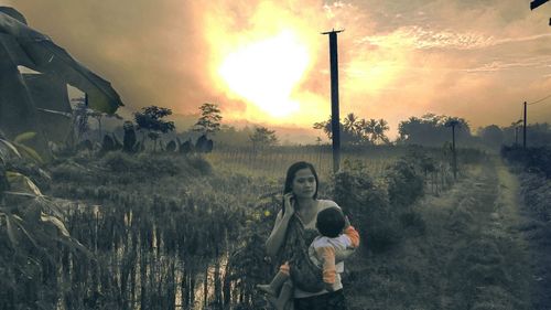 Children standing on field against sky