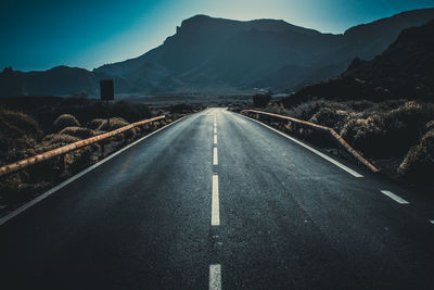 Road leading towards mountains against sky