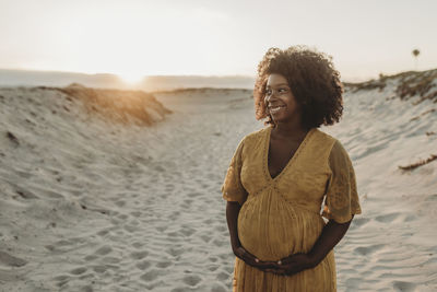 Young woman standing at beach against sky