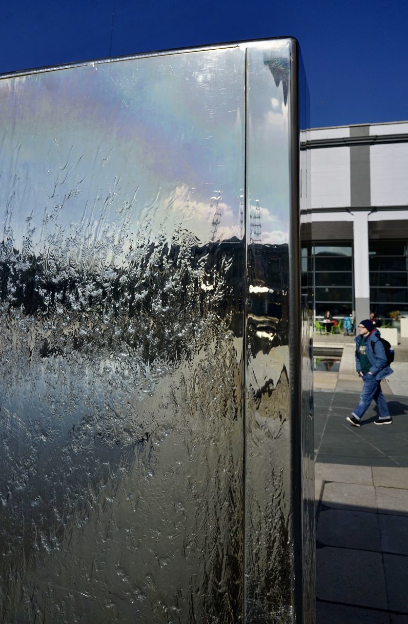 MAN ON GLASS WINDOW AGAINST SKY