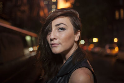 Portrait of young woman looking away in city at night