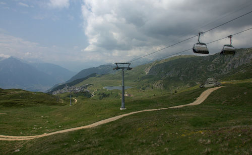 Overhead cable car over mountains against sky