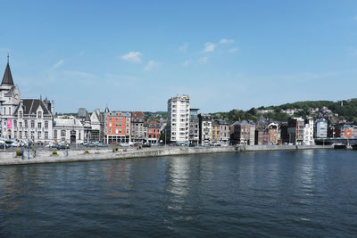 Buildings by river against sky in town