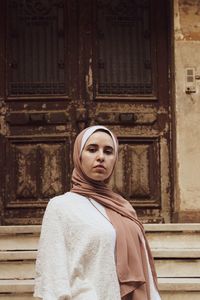 Portrait of a beautiful young woman standing against building