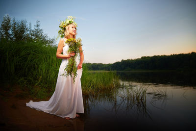 Rear view of woman standing against lake